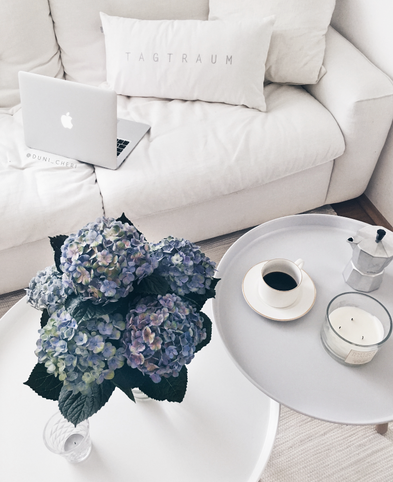 Weiße Couch mit blauen Hortensien Macbook und Kaffee